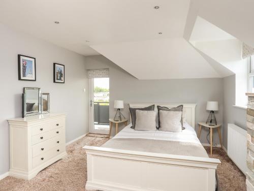 a white bedroom with a white bed and a window at The Old Coal Yard in Cemaes Bay