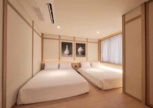 two beds in a room with a window at UH Suite Central Seoul in Seoul