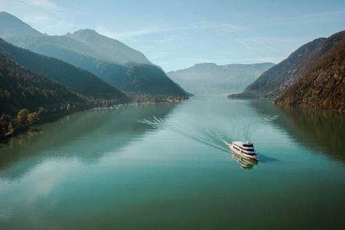 a boat on a river in a valley with mountains at Hotel St. Georg zum See in Maurach