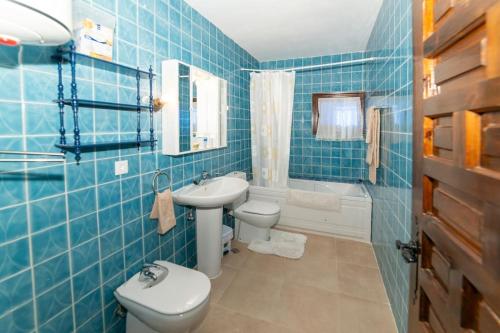 Baño de azulejos azules con aseo y lavamanos en Finca el Palomar de la Viña, en Madrid
