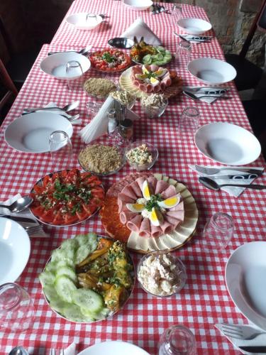 a table with plates of food on a red and white checked table cloth at Seosko turističko domaćinstvo Stanišić in Kalna