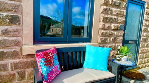 a bench with two pillows sitting under a window at Chapel row 4 in Wirksworth