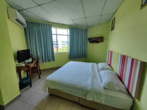 a bedroom with a bed and a desk and a television at Century Hotel Inanam in Kota Kinabalu