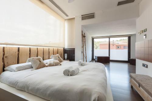 een slaapkamer met een groot wit bed en handdoeken bij Espai Oliveres in Papiol