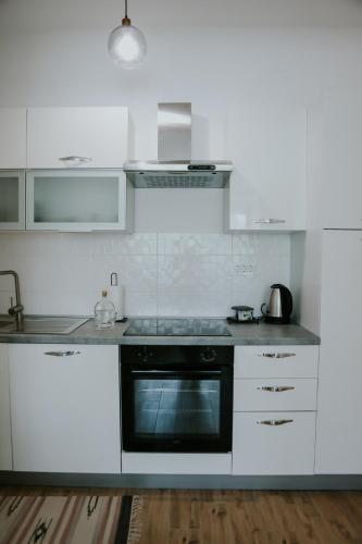 a kitchen with white cabinets and a black oven at Apartman Nikola in Gospić