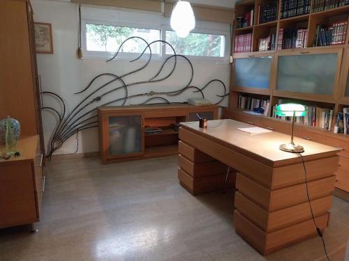 an office with a desk and a tv and book shelves at Cozy apartment close to the sea in Perea