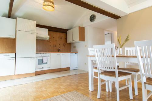 eine Küche mit weißen Schränken sowie einem Tisch und Stühlen in der Unterkunft Lions Apartments - Erholung und Vergnügen in Bad Tatzmannsdorf in Jormannsdorf