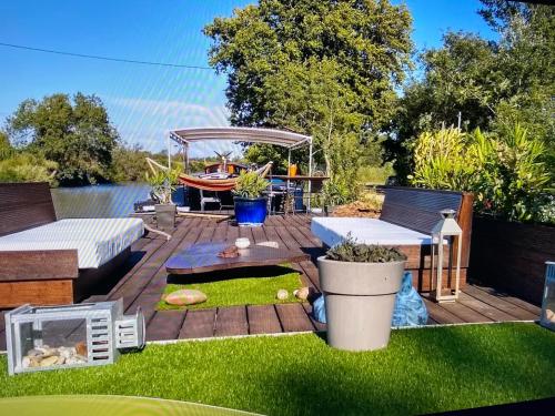 une arrière-cour avec une terrasse et un bateau dans l'eau dans l'établissement Chambre d'hôte insolite sur une péniche, à Portiragnes