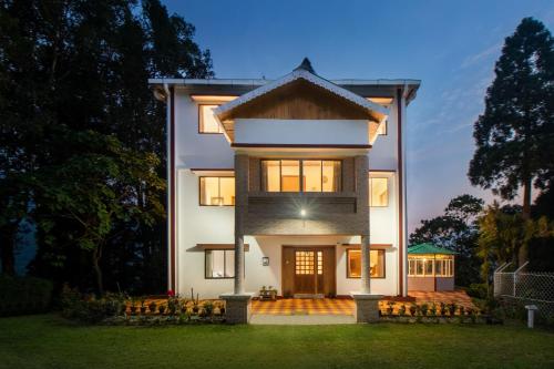 a large white house with a front yard at StayVista's Tree Tops & Tea Trails - Mountain-View Villa Amidst Tea Plantation with Telescope & Gazebo in Darjeeling