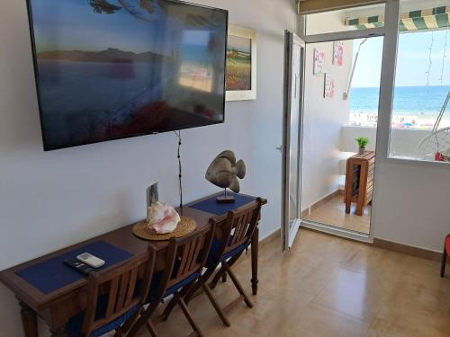 a dining room with a table with chairs and a television at Apartamento 108 Hotel Flamero in Matalascañas