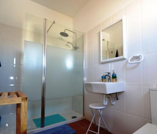 een badkamer met douche, wastafel en spiegel bij T3 Olhos de Água in Albufeira