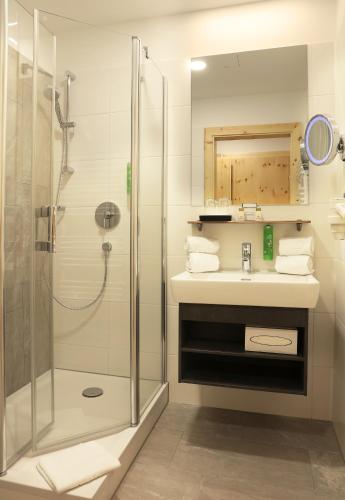 a bathroom with a shower and a sink at JUFA Alpenhotel Saalbach-Jokercard im Sommer inklusive in Saalbach Hinterglemm