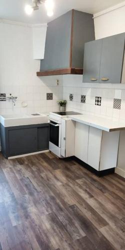 une cuisine avec des armoires blanches et un plancher en bois dans l'établissement Maison lumineuse & jardin privé, à Confolens