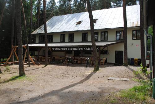 a large white building with a sign in front of it at Penzion a Restaurace Kamínek in Doksy