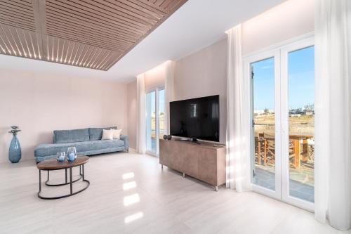 a living room with a couch and a tv at Le Ciel Suites & Villas in Mýkonos City