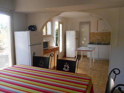 Il comprend une cuisine équipée d'un réfrigérateur et d'une table avec des chaises. dans l'établissement Plein SUD, 5 mn de la mer, grand logement 8 personnes, à Marseillan