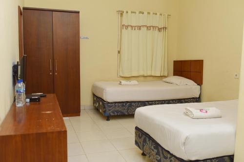 - une chambre d'hôtel avec 2 lits et une commode dans l'établissement Al-Ghani Syariah Mitra RedDoorz, à Padang