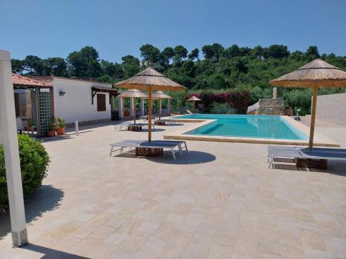 una piscina con sombrillas y bancos junto a un edificio en Hotel Parco Carabella partner Elite Hotels en Vieste