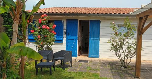 Saint-Vivien-de-MédocMaisonnette de charme entre plages et estuaire的院子里有蓝色门和椅子的房子