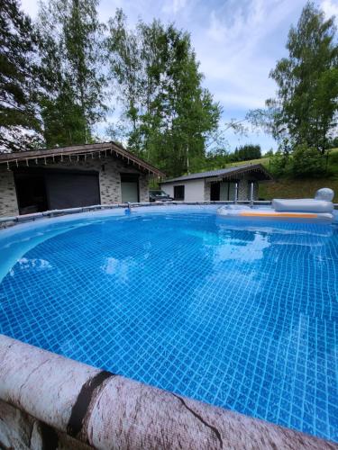 a large blue swimming pool in front of a house at Leśny chillout in Solina