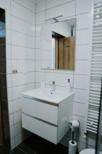 a white bathroom with a sink and a mirror at Apartman Nikola in Gospić