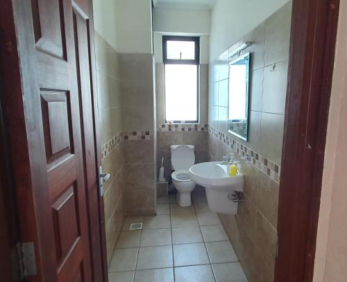 a bathroom with a toilet and a sink and a window at Penthouse Five - The Beautiful 3Br En-suite Apt in Mombasa