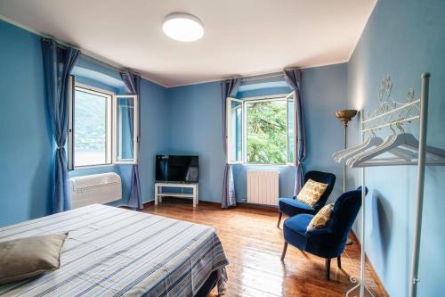 een slaapkamer met blauwe muren en een bed en 2 stoelen bij Lemon Tree Lake View - by MyHomeInComo in Laglio