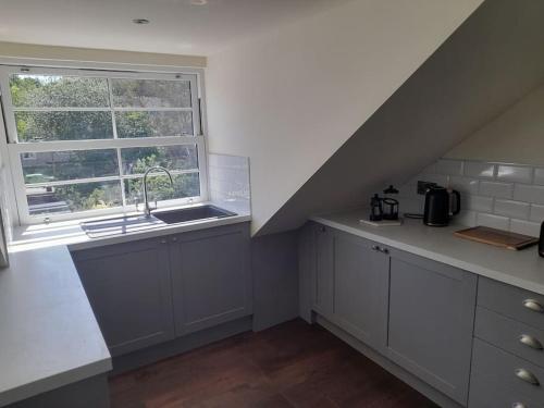 an attic kitchen with a sink and a window at Kirkcudbright Holiday Apartments - Apartment G in Kirkcudbright