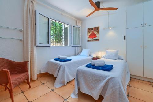 a room with two beds and a chair and a window at Casa Que Sera in Jávea