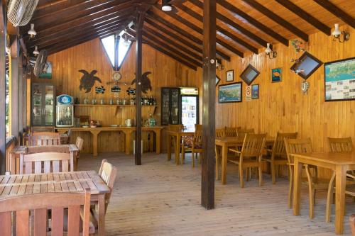 キラリにあるCaretta Caretta Pensionの木製の壁とテーブルと椅子が備わるレストラン
