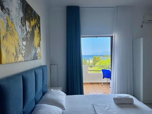 a bedroom with a bed with a blue headboard and a window at Dine Apartments in Ksamil