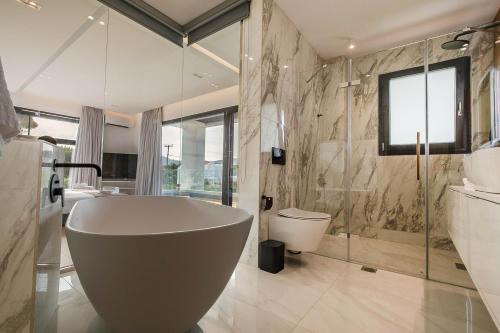 a bathroom with a tub and a toilet and a sink at Armonia Luxury Villa in Ialysos