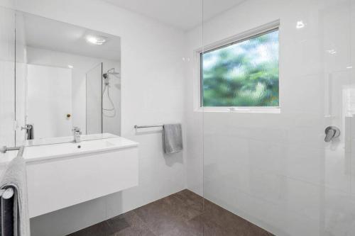 a white bathroom with a sink and a window at Seaview Treehouse - three minute walk to the beach in Lorne