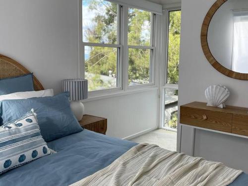 a bedroom with a blue bed and a mirror at Seaview Treehouse - three minute walk to the beach in Lorne