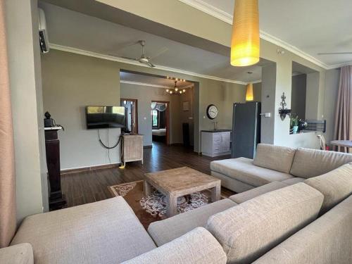 a living room with two couches and a tv at Aquamarina Hotel & Villas in Jambiani