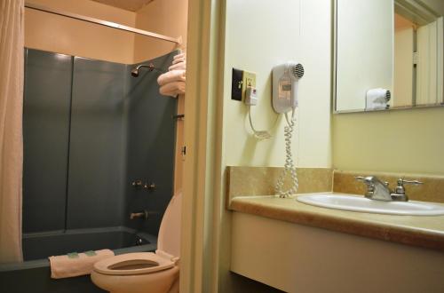 Economy Inn Bluefield في Bluefield: حمام مع مرحاض ومغسلة وهاتف