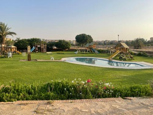 - une piscine dans un parc avec une aire de jeux dans l'établissement A sea view spacious cheering 5 bedroom villa Ain Sokhna "Ain Bay" فيلا كاملة للإيجار قرية العين باي, à Ain Sokhna