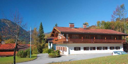 ein großes Holzhaus mit rotem Dach in der Unterkunft Ferienwohnungen am Ganglbach in Bayrischzell