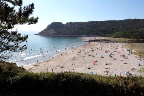 a group of people on a beach near the water at camiño dos faros in Ponteceso