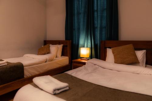a room with two beds and a lamp on a table at Dynasty Hotel Skardu in Skardu