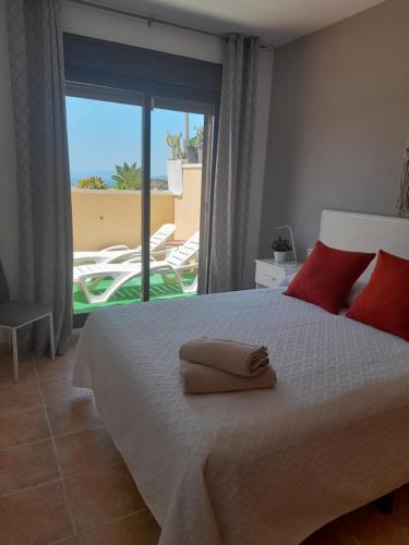 1 dormitorio con 1 cama con almohadas rojas y balcón en Apartamento Serena beach, en Águilas