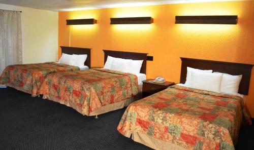 2 camas en una habitación de hotel con paredes de color naranja en Economy Inn Bluefield, en Bluefield