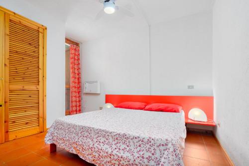 1 dormitorio con 1 cama con almohadas rojas en Casa Vacanza Libeccio 2417, en Cugnana