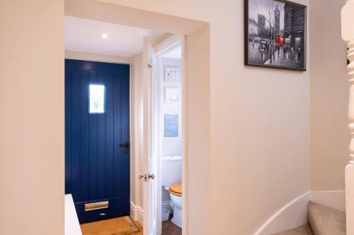 a blue door in a bathroom with a toilet at Sway Corner in Lymington