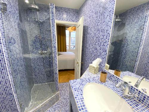 une salle de bain carrelée bleue avec un lavabo et une douche dans l'établissement L'appartement Letac, à Paris