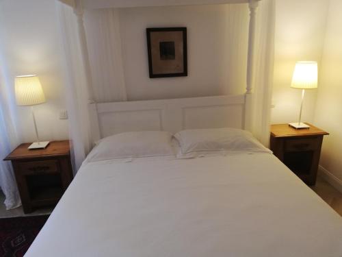 a bedroom with a white bed with two lamps at Les 3 Platanes in Conilhac-Corbières