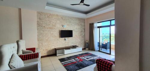 ein Wohnzimmer mit einem TV an einer Backsteinwand in der Unterkunft Penthouse Five - The Beautiful 3Br En-suite Apt in Mombasa
