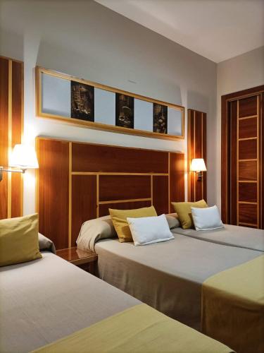 a hotel room with two beds and two lamps at Hotel Carmen in La Carlota