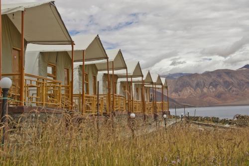 a row of houses with mountains in the background at Pangong Retreat Camp in Spangmik