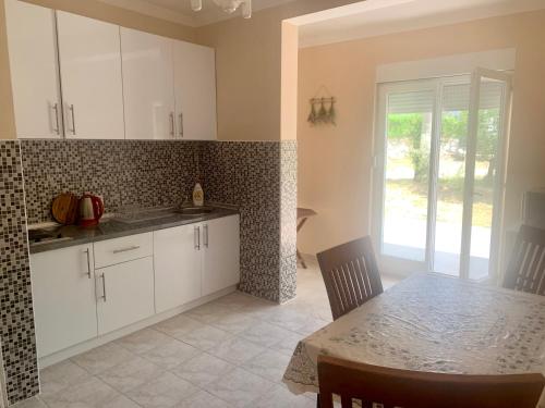 a kitchen with white cabinets and a table and a dining room at Apartments Neira near Dubrovnik in Ivanica